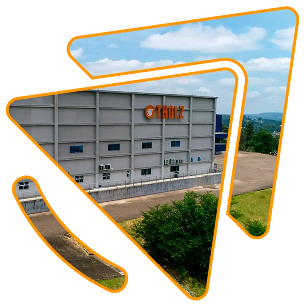 Fachada de la fábrica de Tholz, vista panorámica del edificio industrial con el logo de la marca y áreas verdes alrededor.